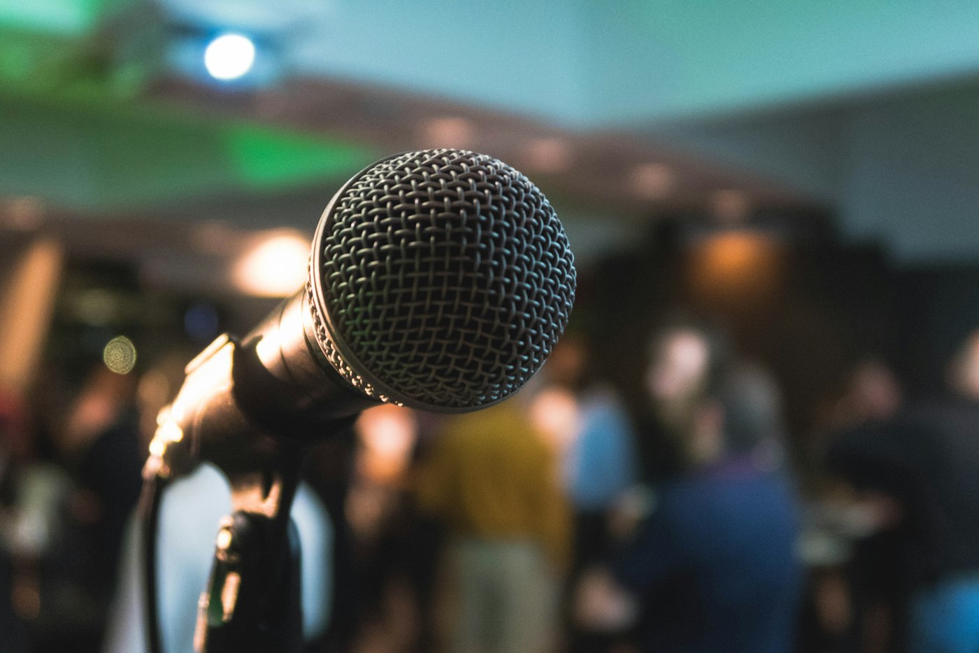 A microphone on a stage, audience in soft focus